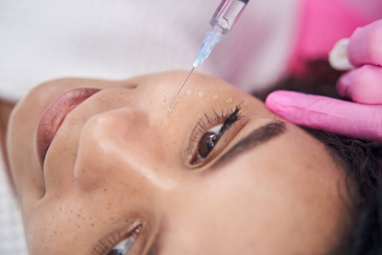 Cosmetologist makes beauty injection on the face of a young woman